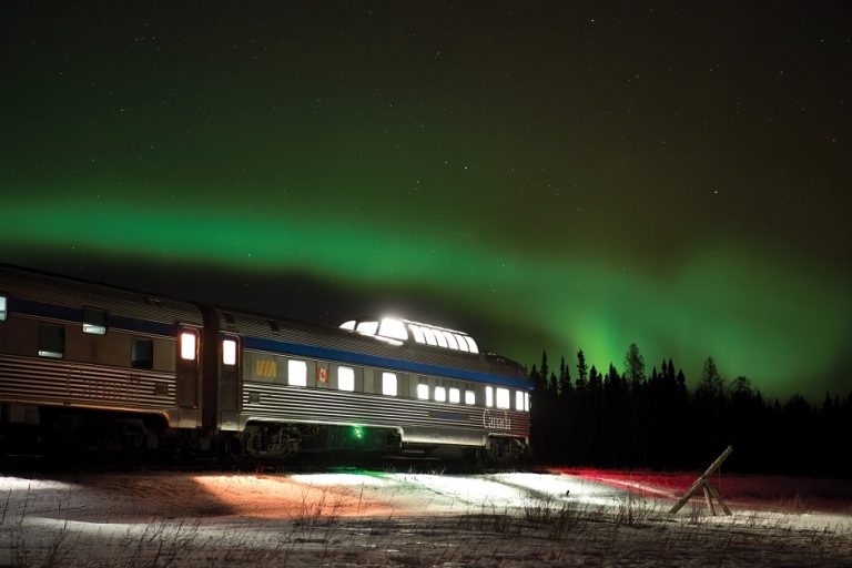 Train VIA Rail Canada sous les aurores boréales vertes dans un paysage enneigé nocturne