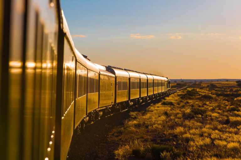 Train Rovos Rail traversant les paysages désertiques de Namibie au coucher du soleil, voitures vertes et dorées