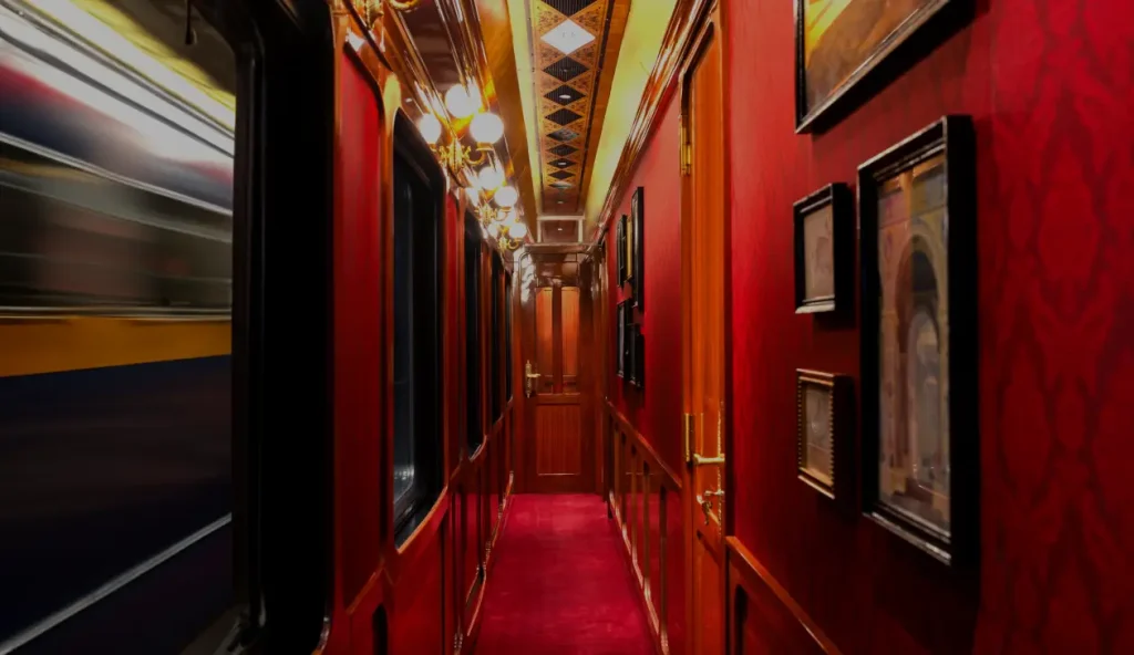 Couloir élégant du Grand Tour France Train avec murs rouges, moquette pourpre et lustres dorés Art Déco