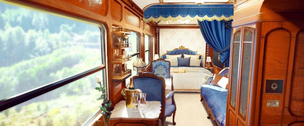 Cabine suite luxueuse du Grand Tour avec lit double, fauteuils bleus velours et boiseries raffinées