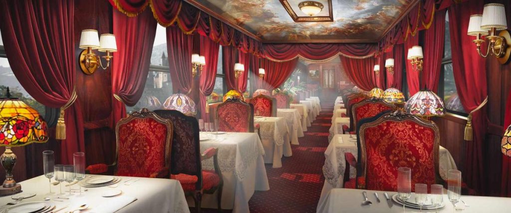 Voiture restaurant Le Grand Tour avec sièges velours rouge, nappes blanches et lampes Tiffany