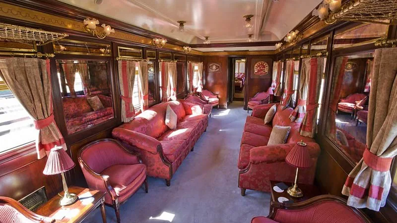 Voiture salon du train Al Andalus avec canapés damassés rouges et bois précieux, luxe ferroviaire