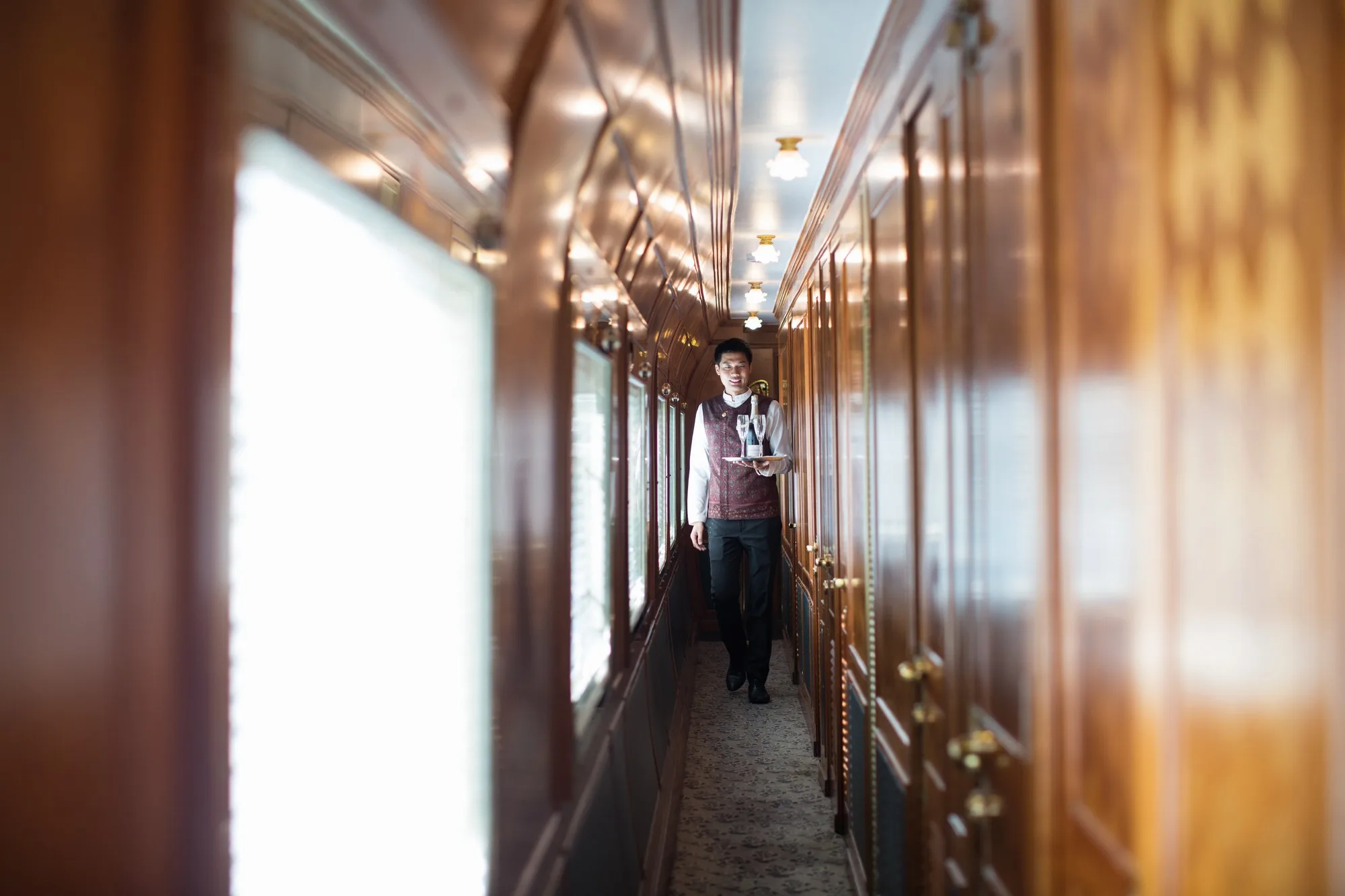 Steward de l'Eastern Oriental Express servant dans le couloir aux boiseries d'acajou