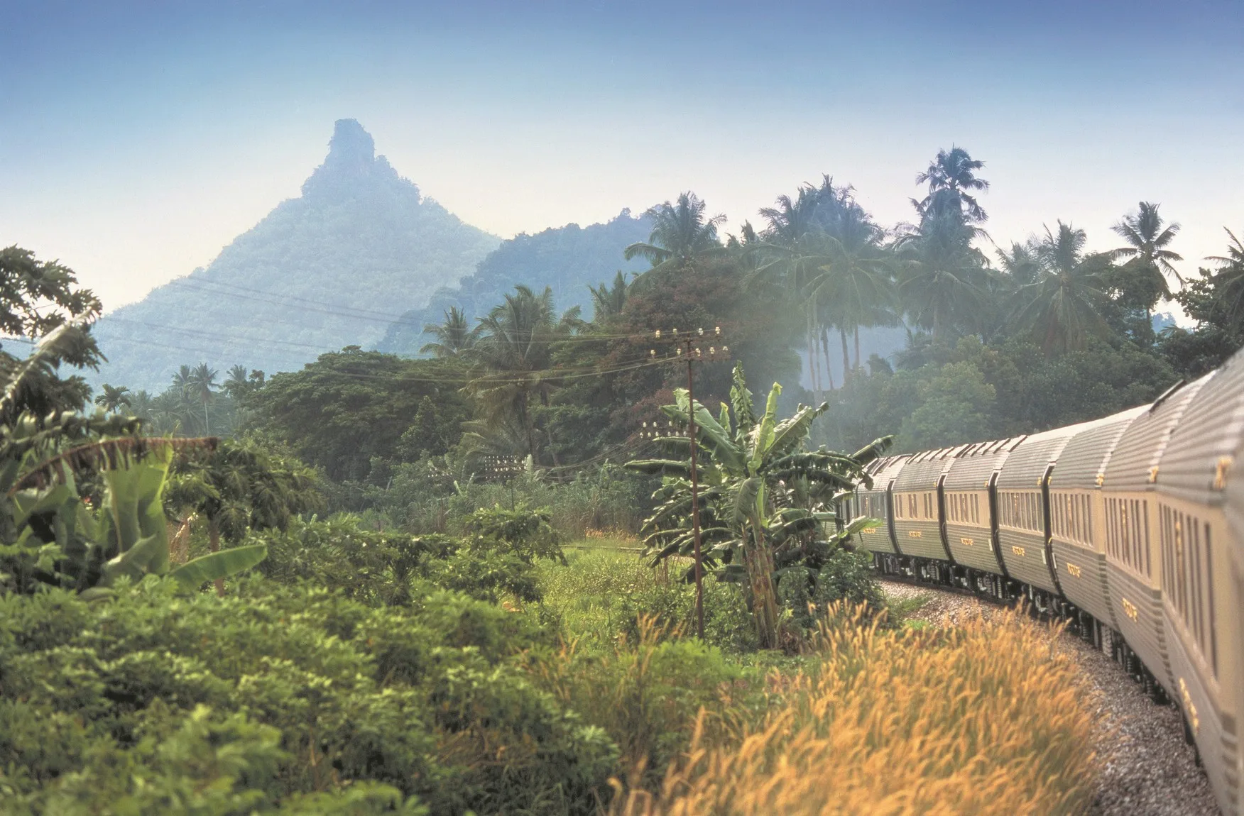 Eastern Oriental Express traversant la jungle tropicale de Malaisie avec montagne en arrière-plan