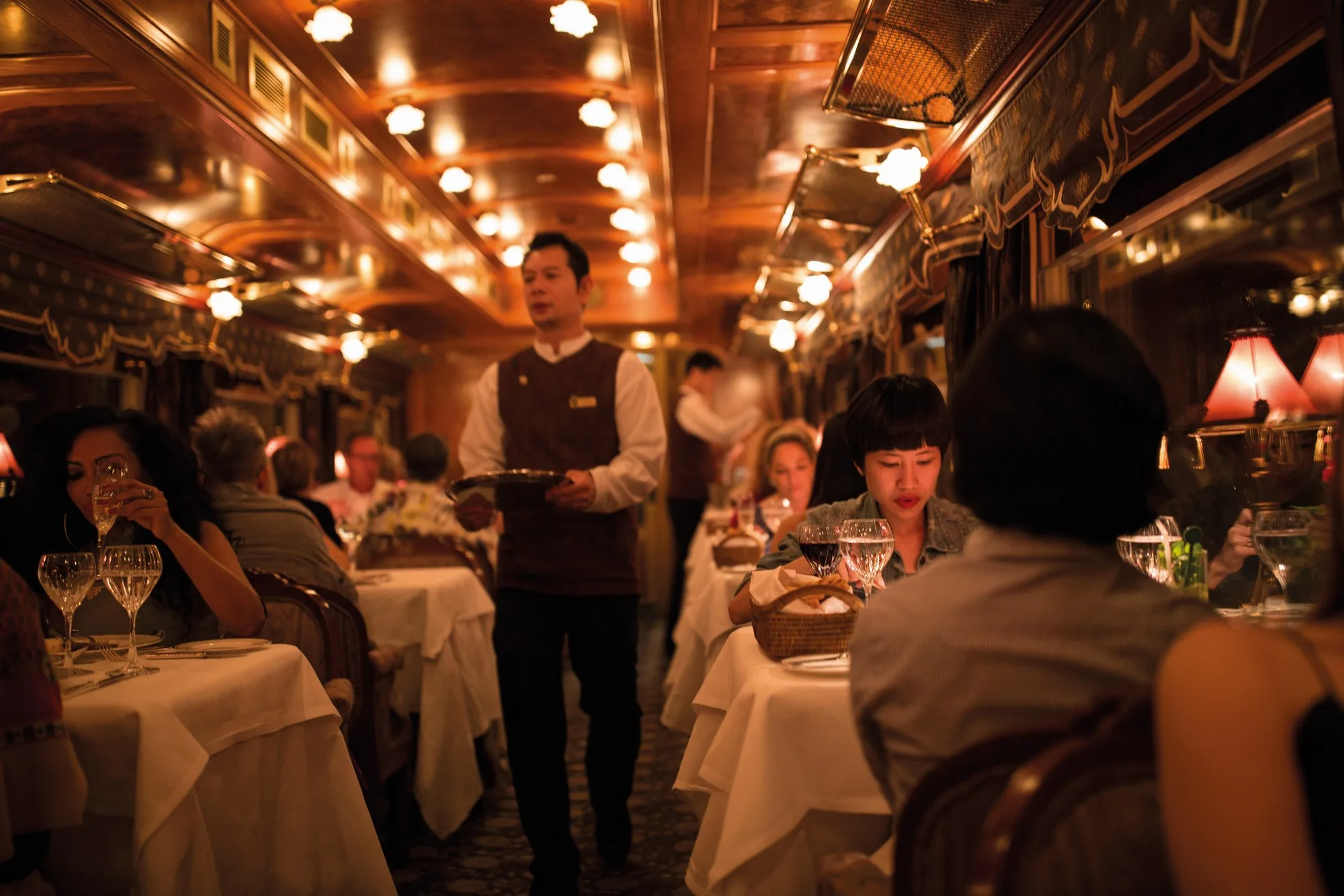 Dîner gastronomique dans le wagon-restaurant de l'Eastern Oriental Express avec passagers et steward