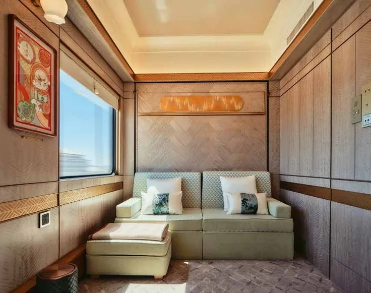 Suite luxe Golden Eagle Silk Road Express avec canapé beige, marbre doré et hublot panoramique