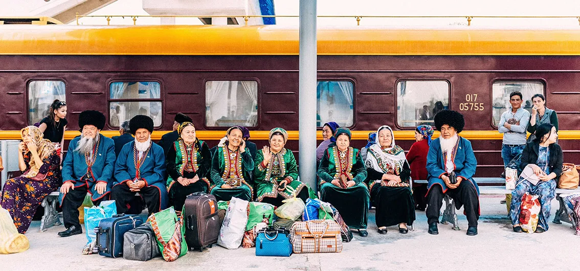 Population locale en tenue traditionnelle au quai de la gare en Ouzbékistan devant l'Orient Silk Road Express