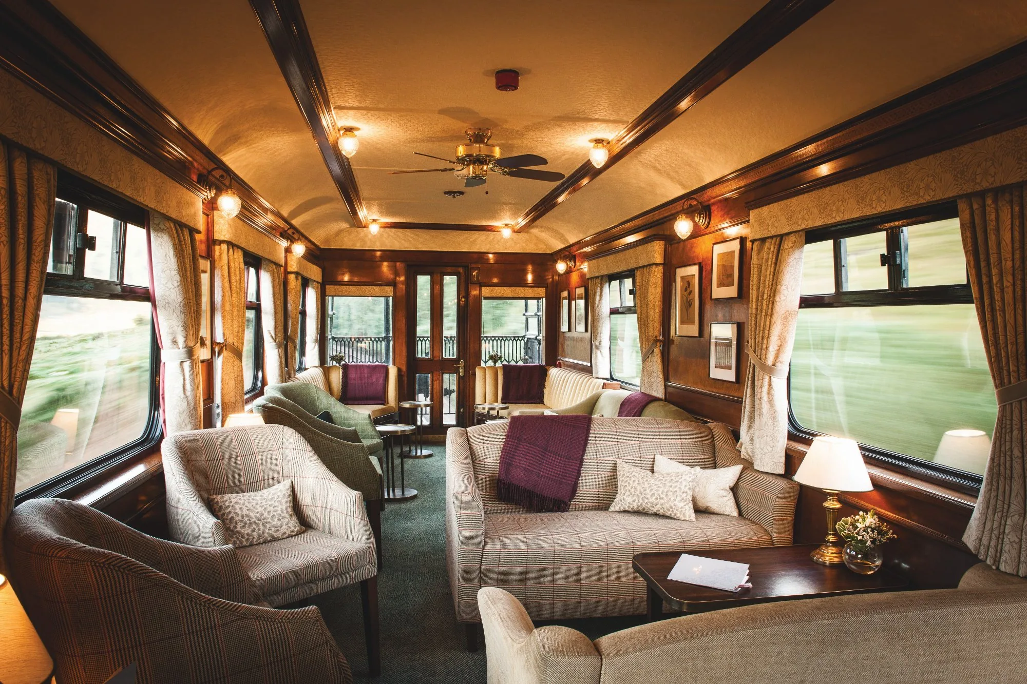 Salon lounge luxueux du Belmond Royal Scotsman — fauteuils en tweed écossais, boiseries acajou et lumières dorées