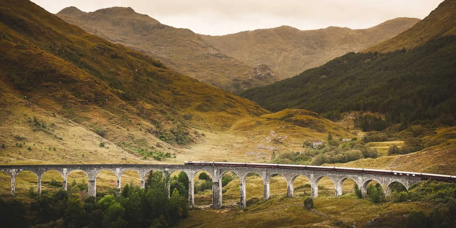Royal Scotsman traversant un viaduc des Highlands écossais — paysage de montagne brumeux et verdoyant