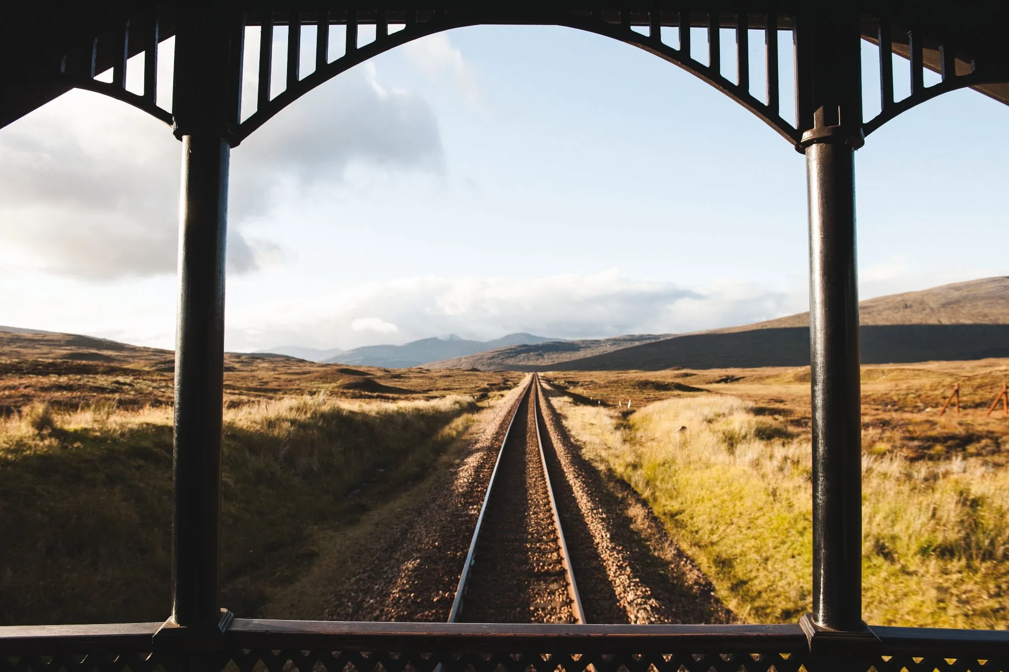Vue depuis la véranda du Royal Scotsman — voies ferrées filant vers l'horizon des Highlands sauvages d'Écosse