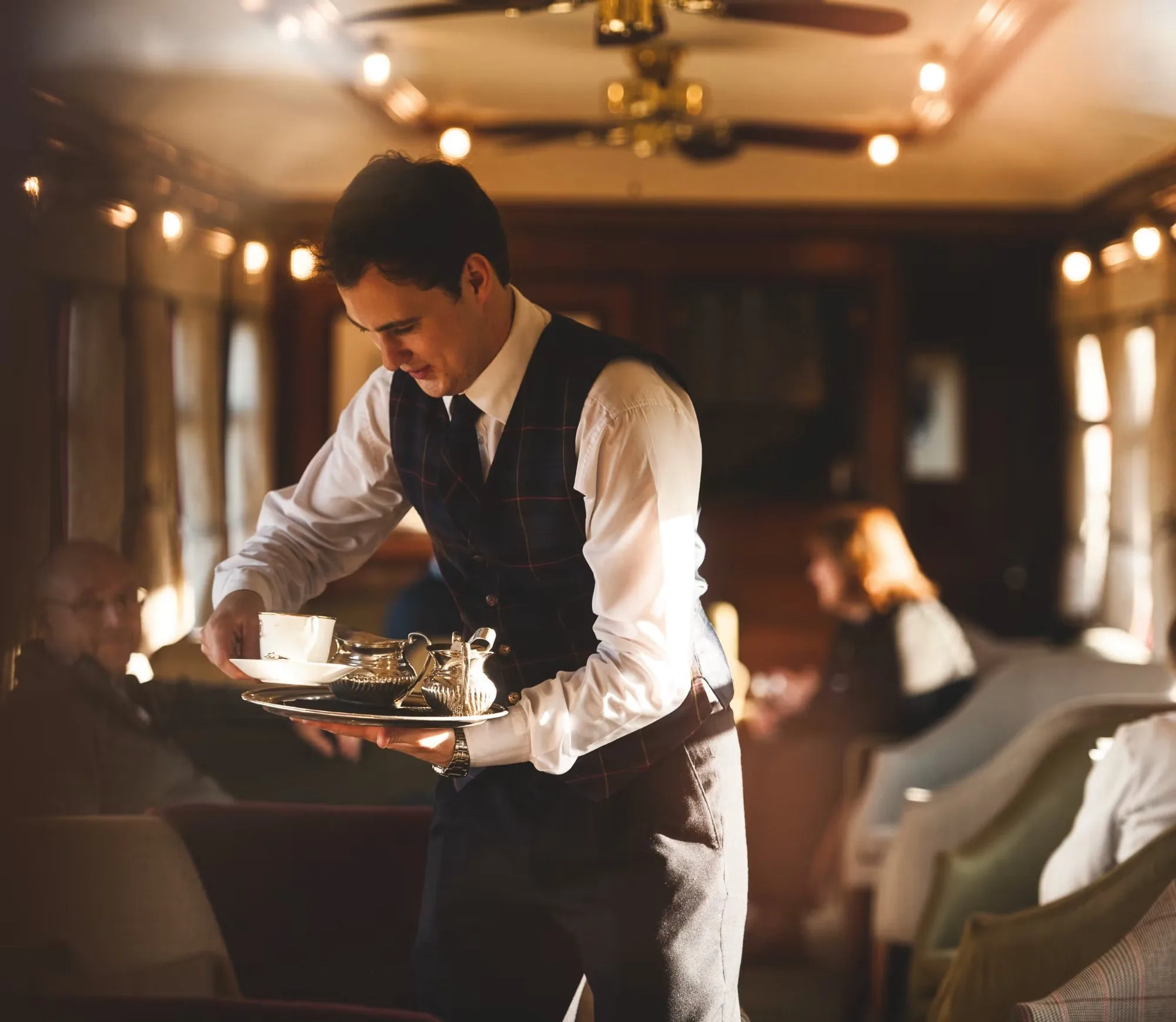 Service raffiné à bord du train de luxe Royal Scotsman — steward apportant le thé dans la voiture observation