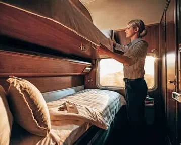 Hôtesse préparant la couchette dans une cabine Gold du train The Ghan au coucher du soleil
