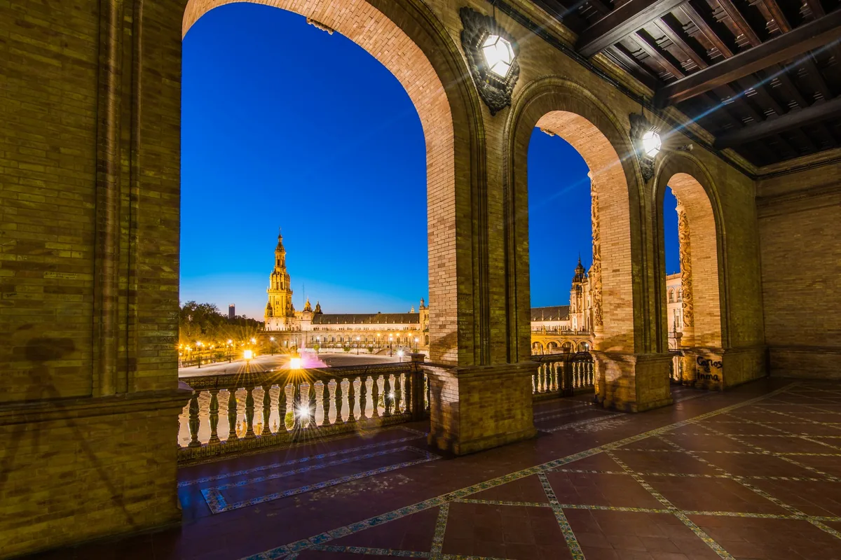 Plaza de España de Séville illuminée à l'heure bleue, point de départ du train Al Andalus