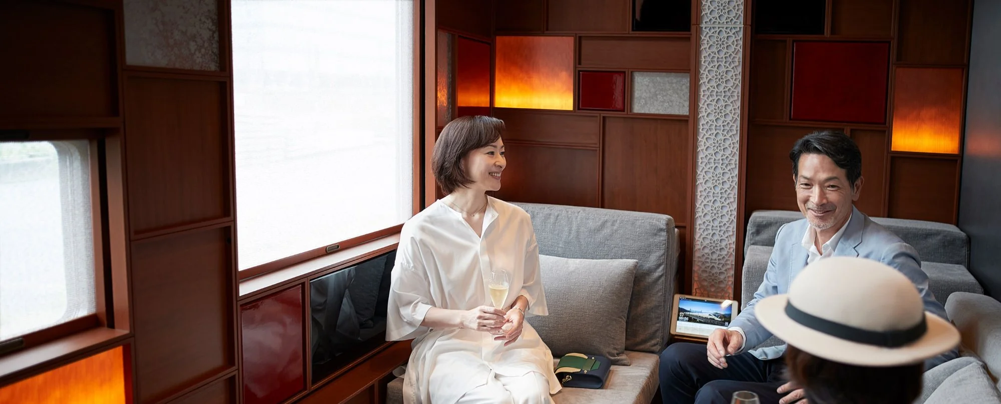 Voyageurs sirotant du champagne dans le lounge du Train Suite Shiki-Shima — train de luxe japonais JR East 2026