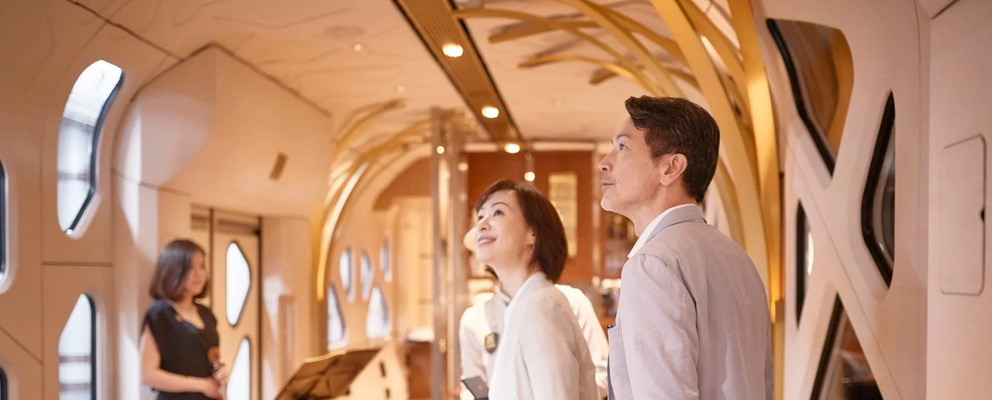 Voyageurs dans le couloir du lounge Komorebi du Shiki-Shima — atmosphère intimiste du train de luxe japonais