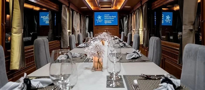 Wagon-restaurant du Blue Jasmine Train dressé pour le dîner, nappes blanches et verres à pied