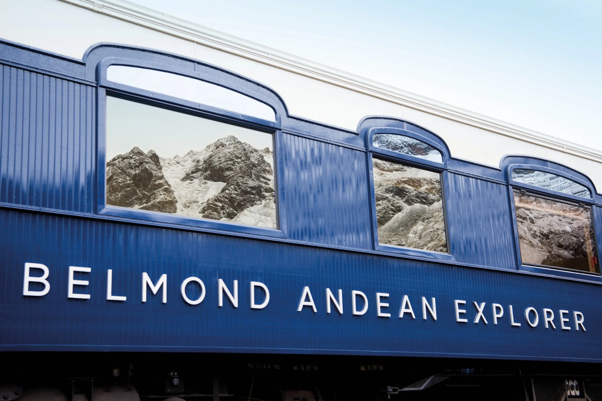 Logo Belmond Andean Explorer sur les fenêtres du train — reflets montagne Andes Pérou
