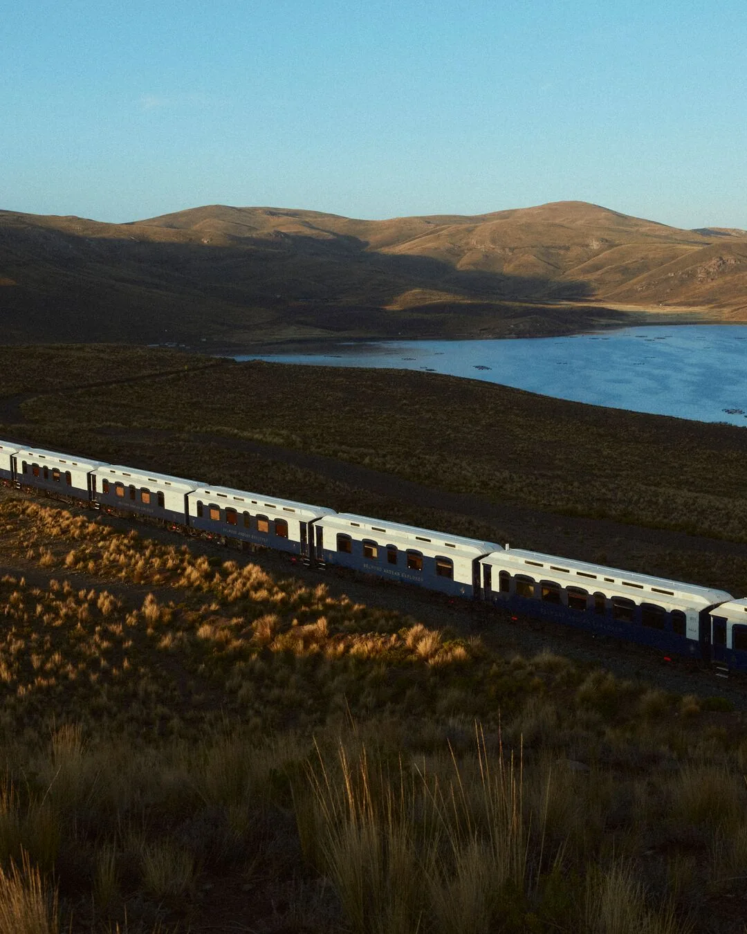 Belmond Andean Explorer longeant un lac d'altitude au coucher du soleil dans les Andes péruviennes