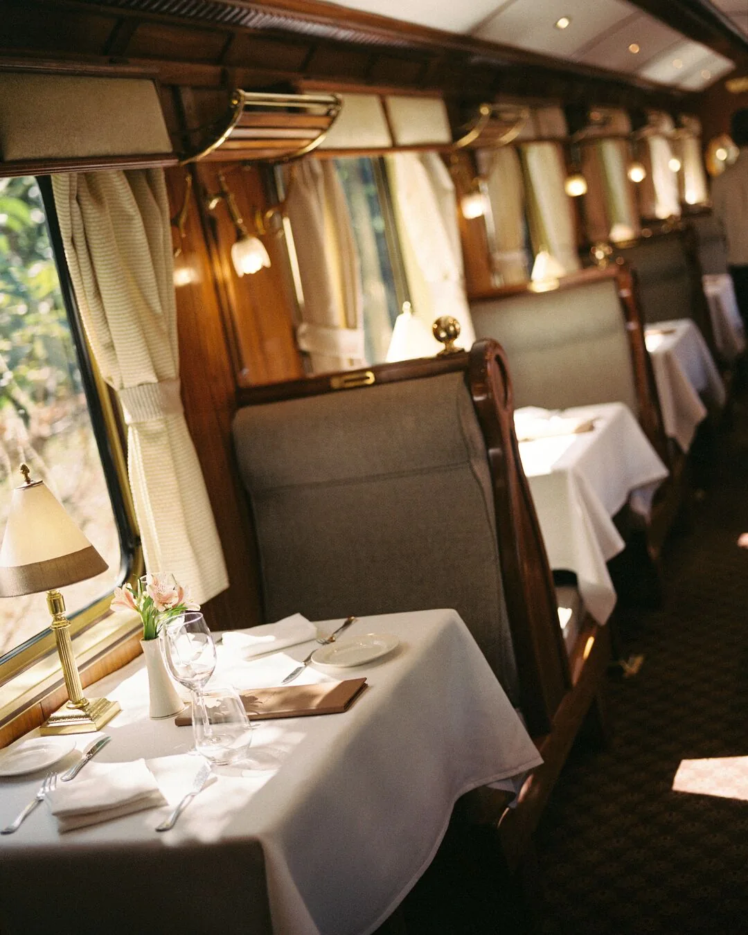 Intérieur du wagon-restaurant du Belmond Hiram Bingham — boiseries, tables blanches, ambiance Pullman
