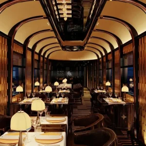 Voiture restaurant luxueuse de l'Orient Express avec tables dressées, lampes art déco et boiseries élégantes