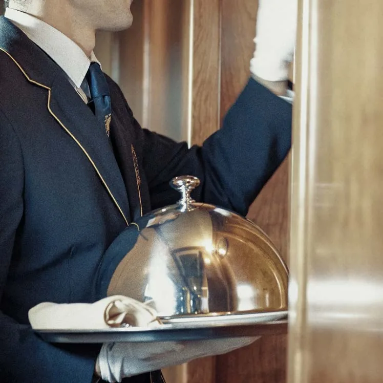 Service à la cloche d'argent par l'équipage en uniforme bleu du Transcantábrico Gran Lujo dans la voiture-restaurant